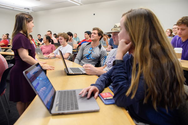 Woman stands in front of class as students look on.