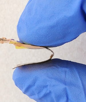 gloved fingers bending the flexible computer chip