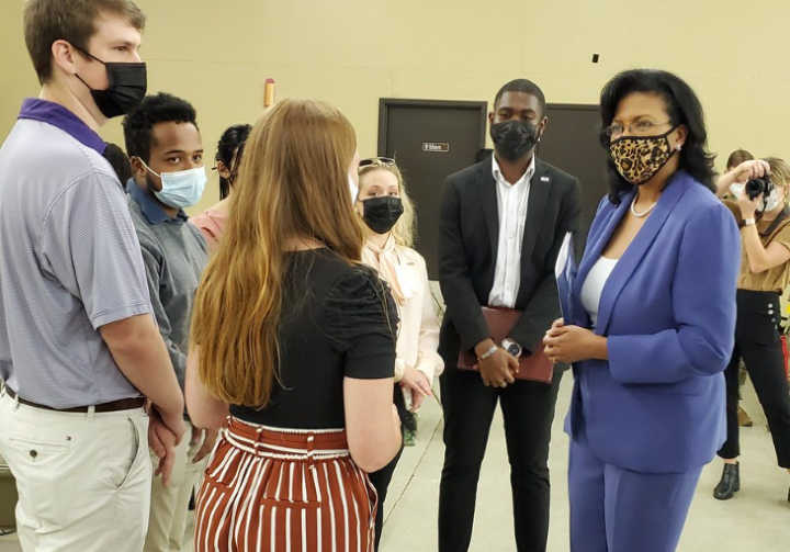 students stand in a circle around dr. kim hunter reed