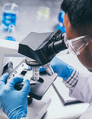 Scientist examining a slide under a microscope.