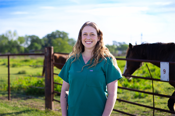 Saige Annison standing in a horse pasture